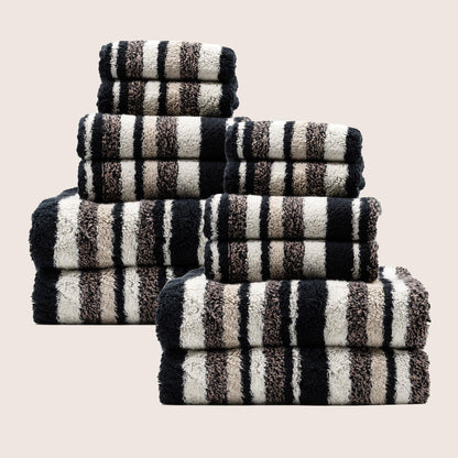 Stack of plush striped towels in dark and light colors, folded with visible check bands.
