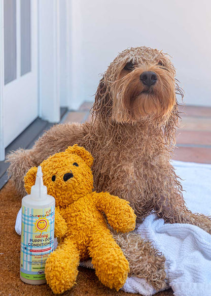 Calming™ Puppy + Dog Conditioner bottle standing beside a plush toy