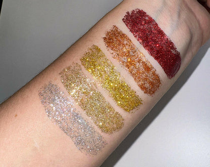 Glitter eyeliner swatches on forearm in silver, gold, and dark red