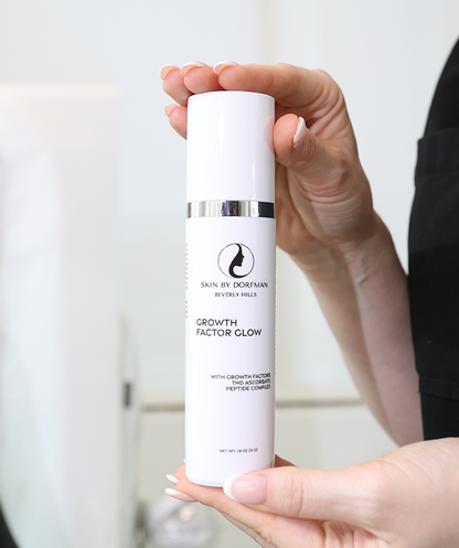 Facial serum bottle held in hand, silver ring around cap