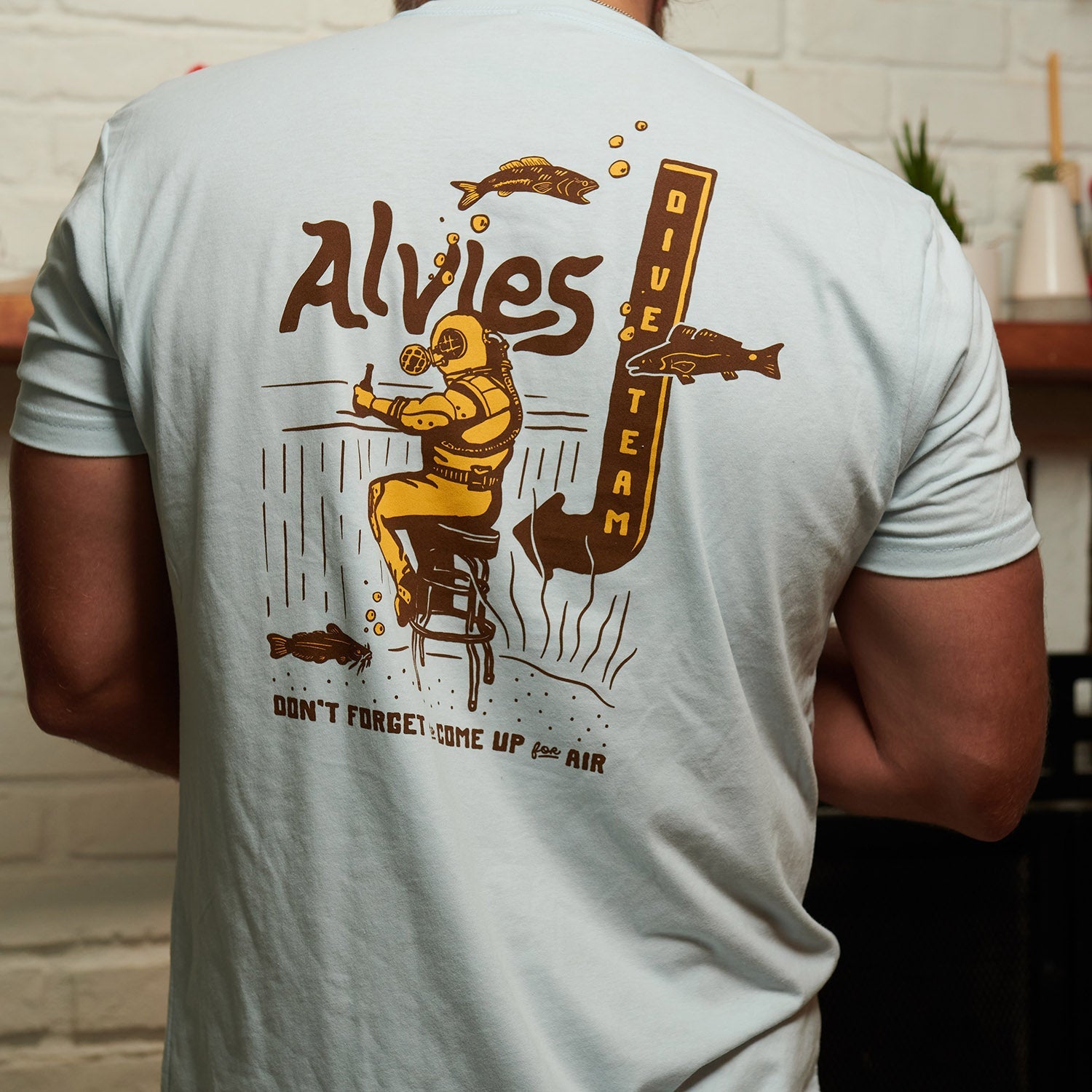 Light blue T-shirt back view with large diver graphic and vertical text