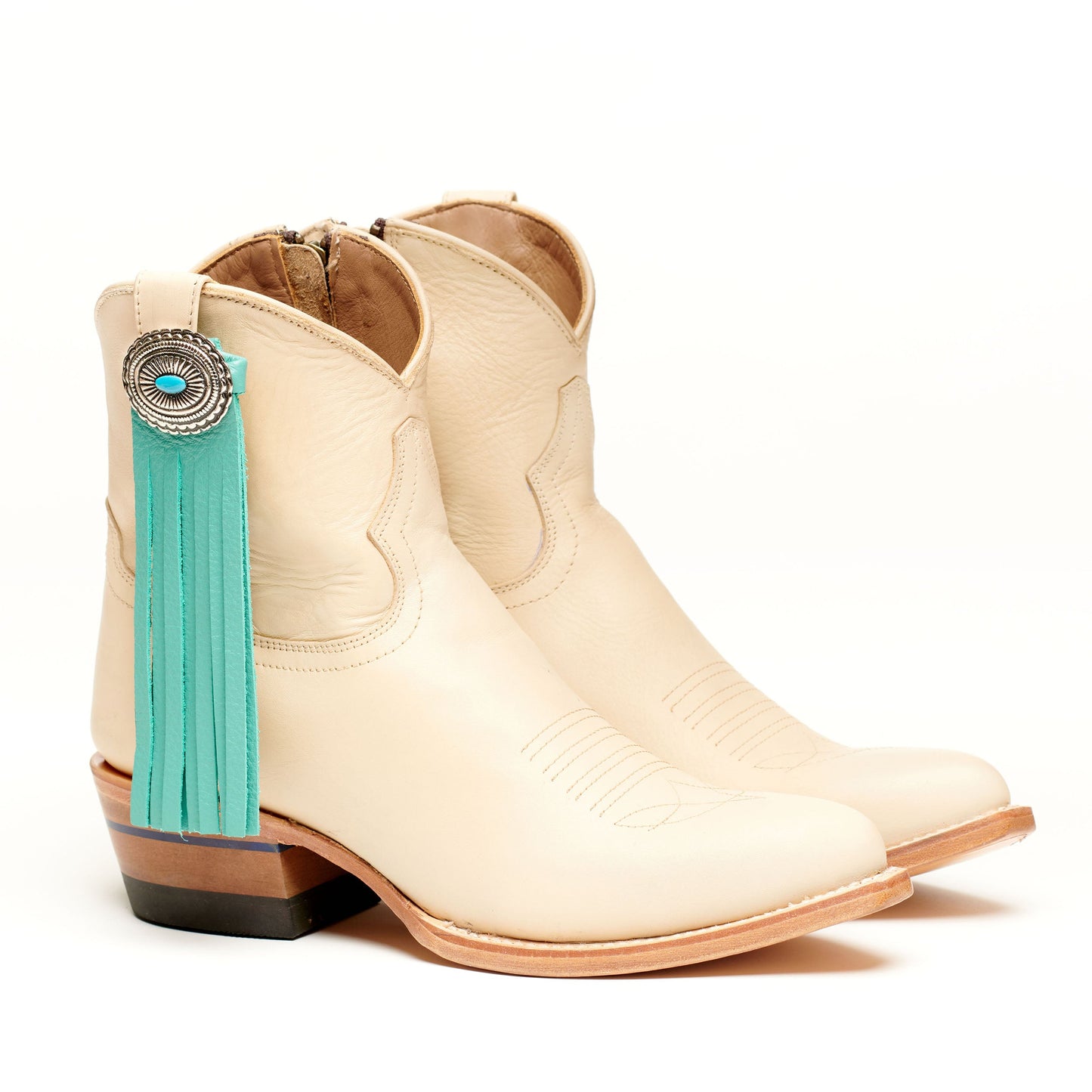 Cream cowboy boots with teal fringe tassel and concho medallion detail