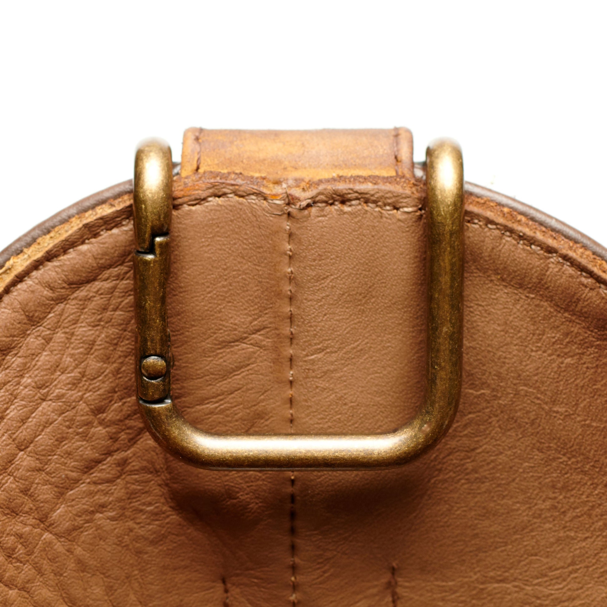 Boot pull clip with gold U-frame and attached leather tab, close-up.