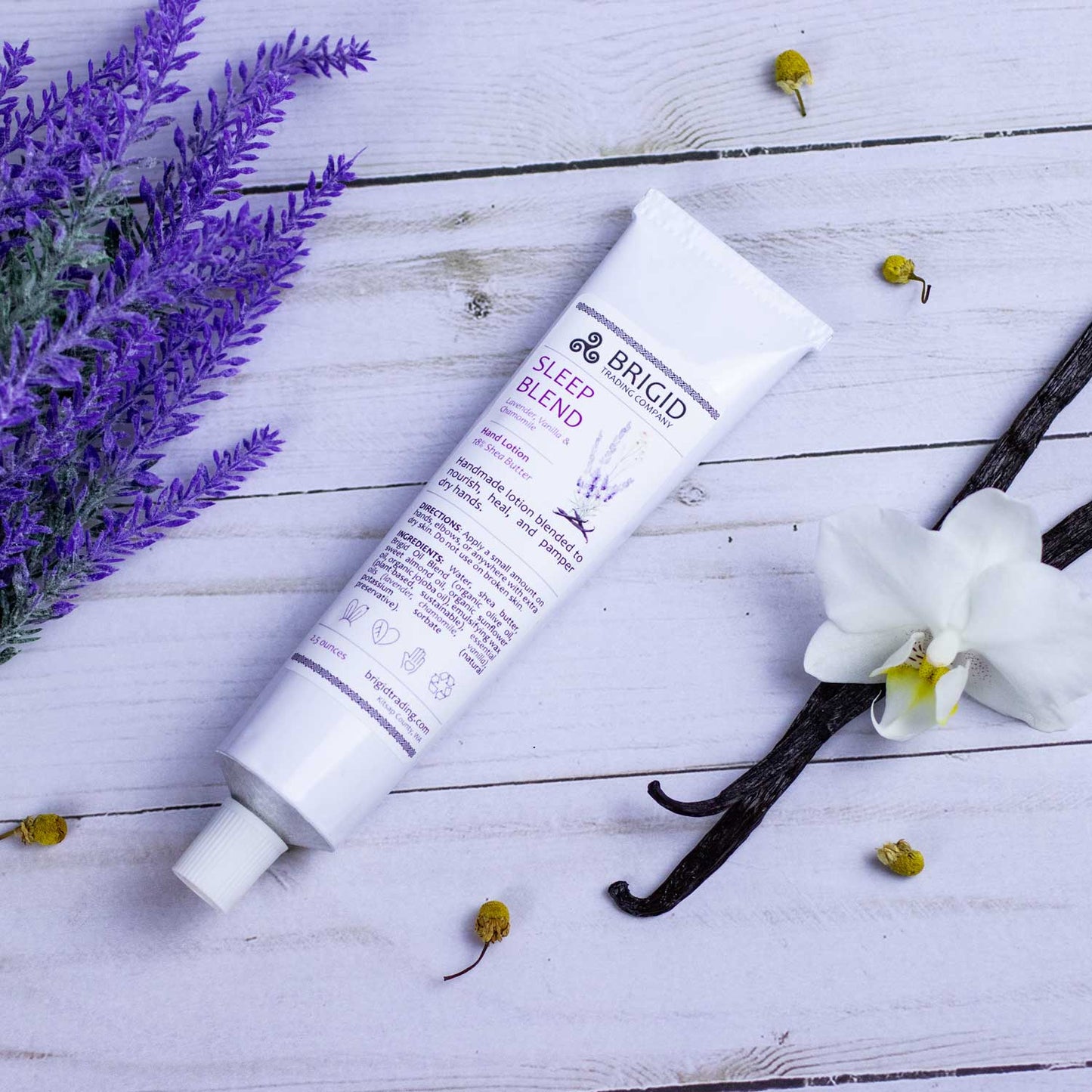 Sleep Blend hand lotion tube lying on flat surface with white cap and vanilla flowers