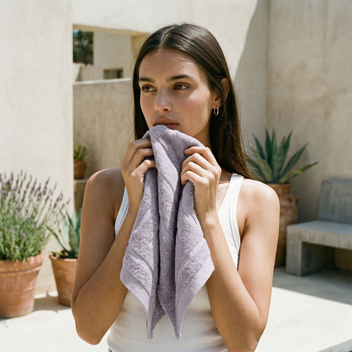 Lilac cotton hand towel held up to a person’s face, neatly folded.