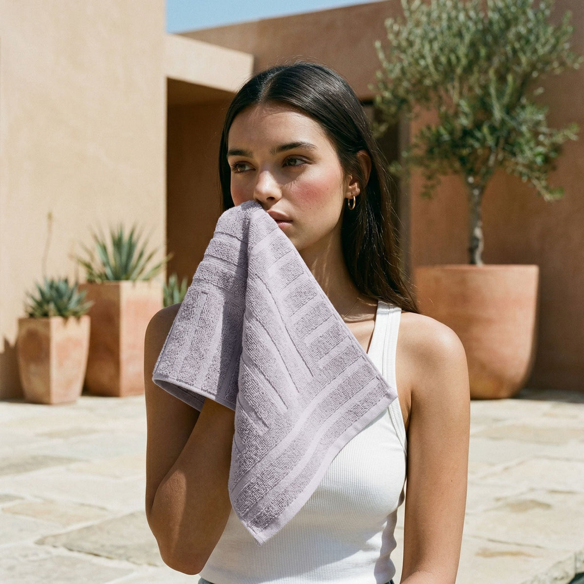Lilac cotton towel with a textured border, folded in the hands of a person.