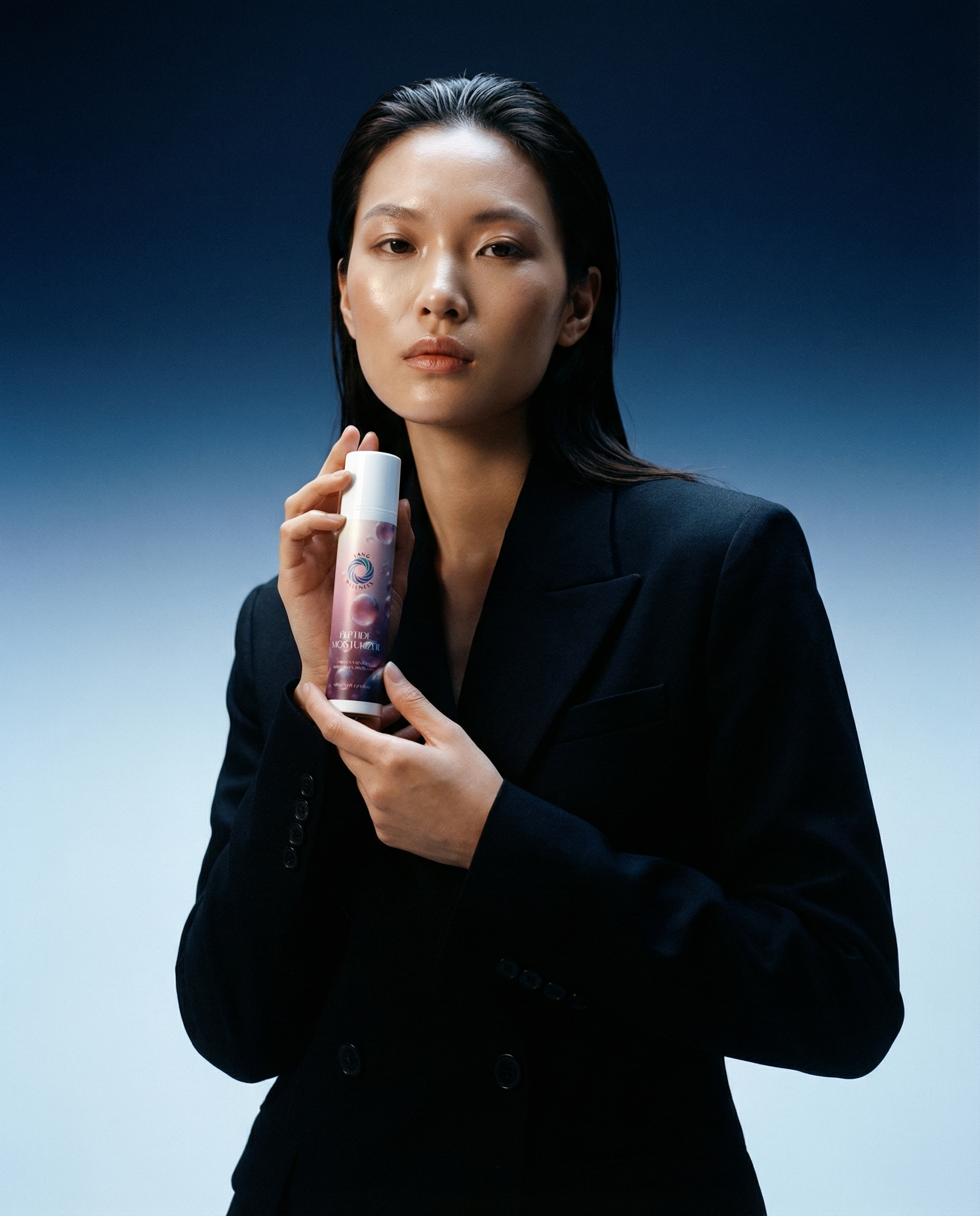 Moisturizer bottle with white cap held in front of a model’s face