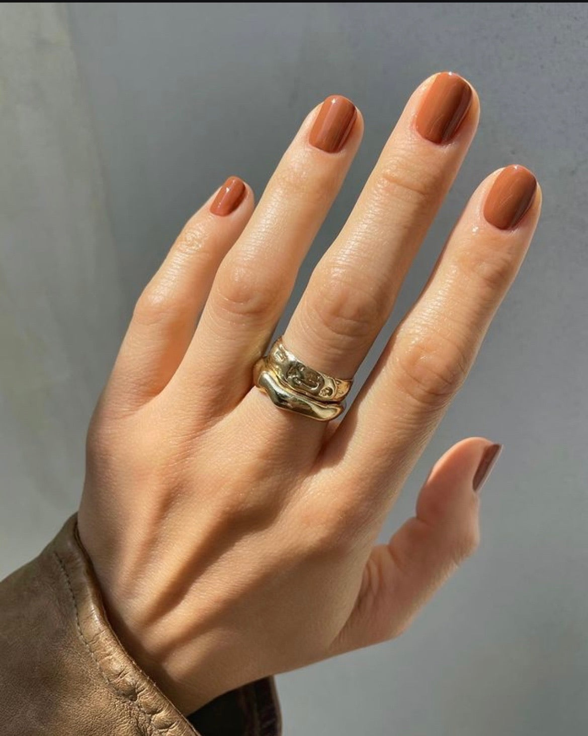 Hand manicure with short nails painted warm bronze-orange