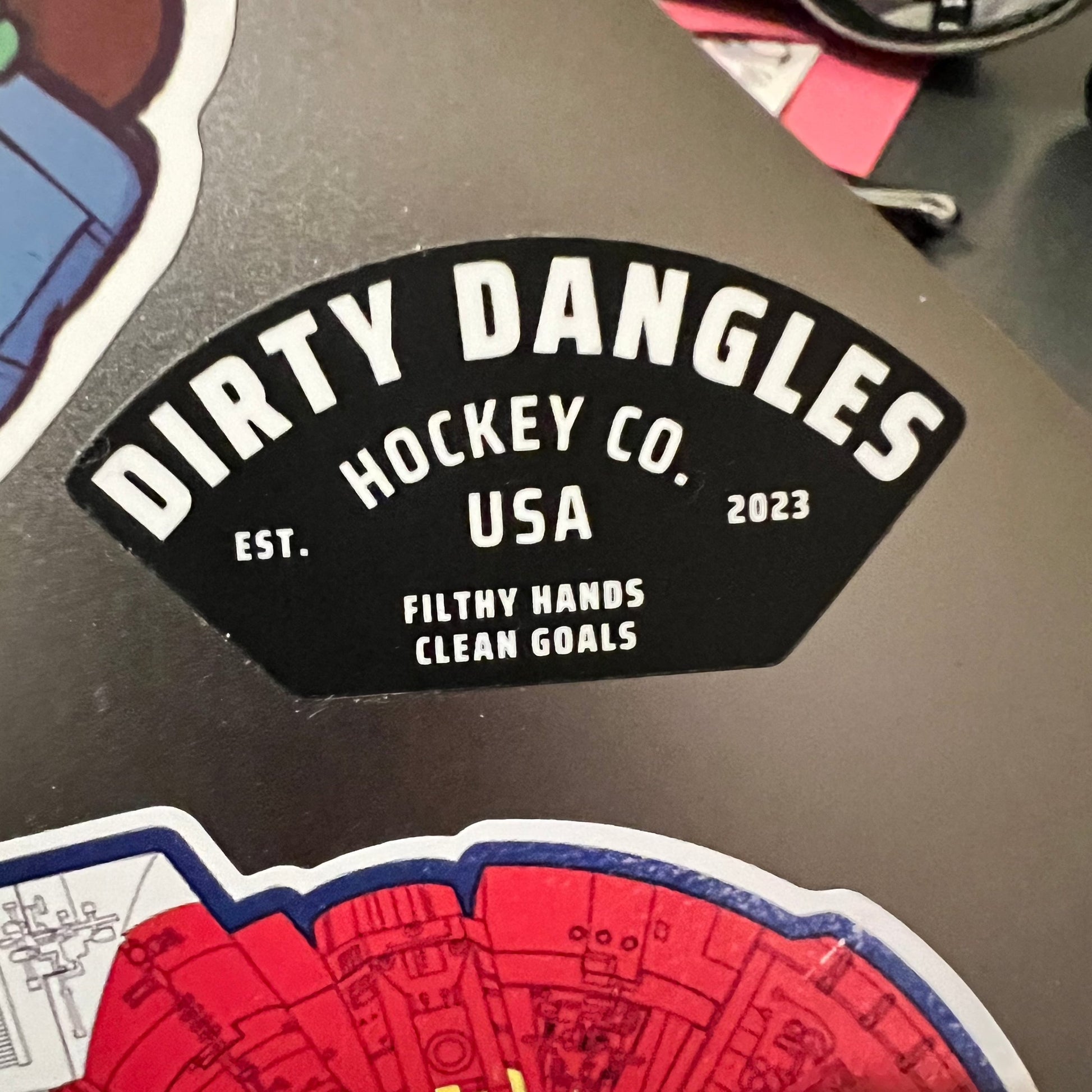 Round hockey sticker with black badge and red-blue rink graphic