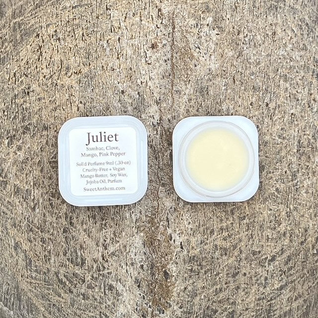 Scented balm tin lid with Juliet label and cream-colored contents