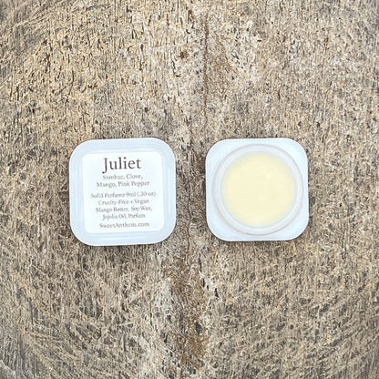 Scented balm tin lid with Juliet label and cream-colored contents