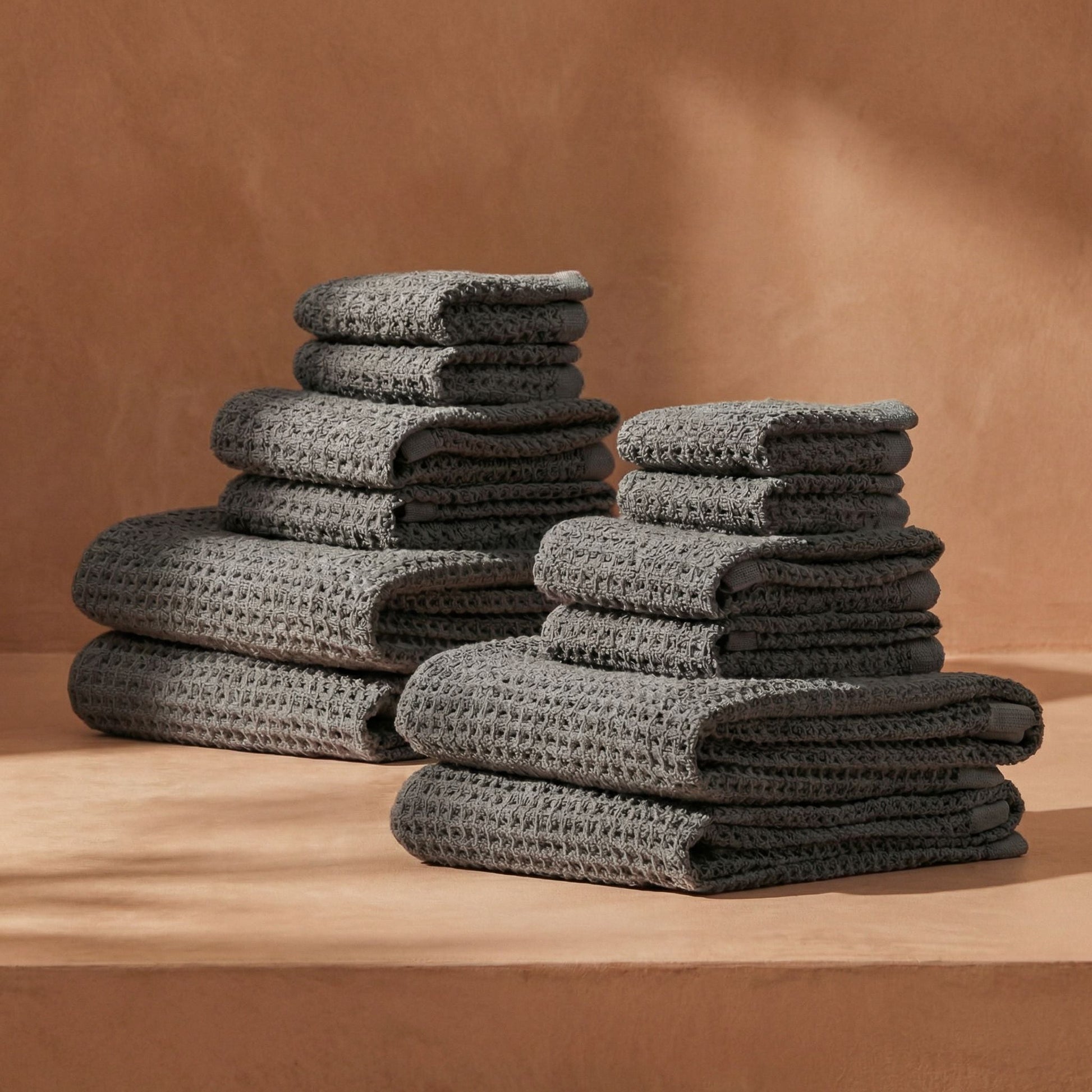 Charcoal waffle cotton towels stacked in neat folds, textured waffle weave