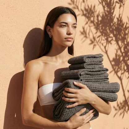 Charcoal waffle cotton towel bundle held in arms, folded waffle texture