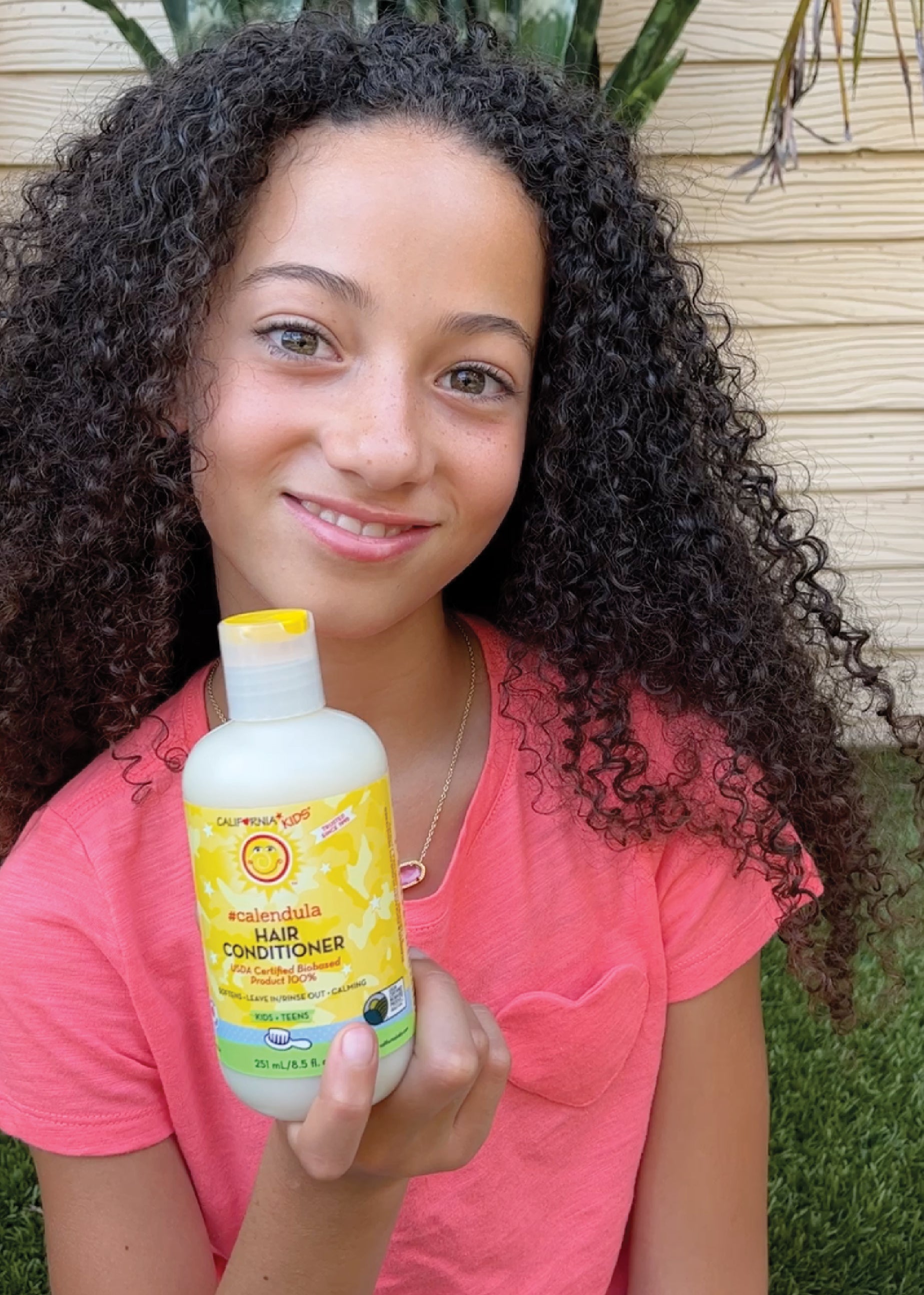 Kids Calendula hair conditioner bottle held in hand, yellow label
