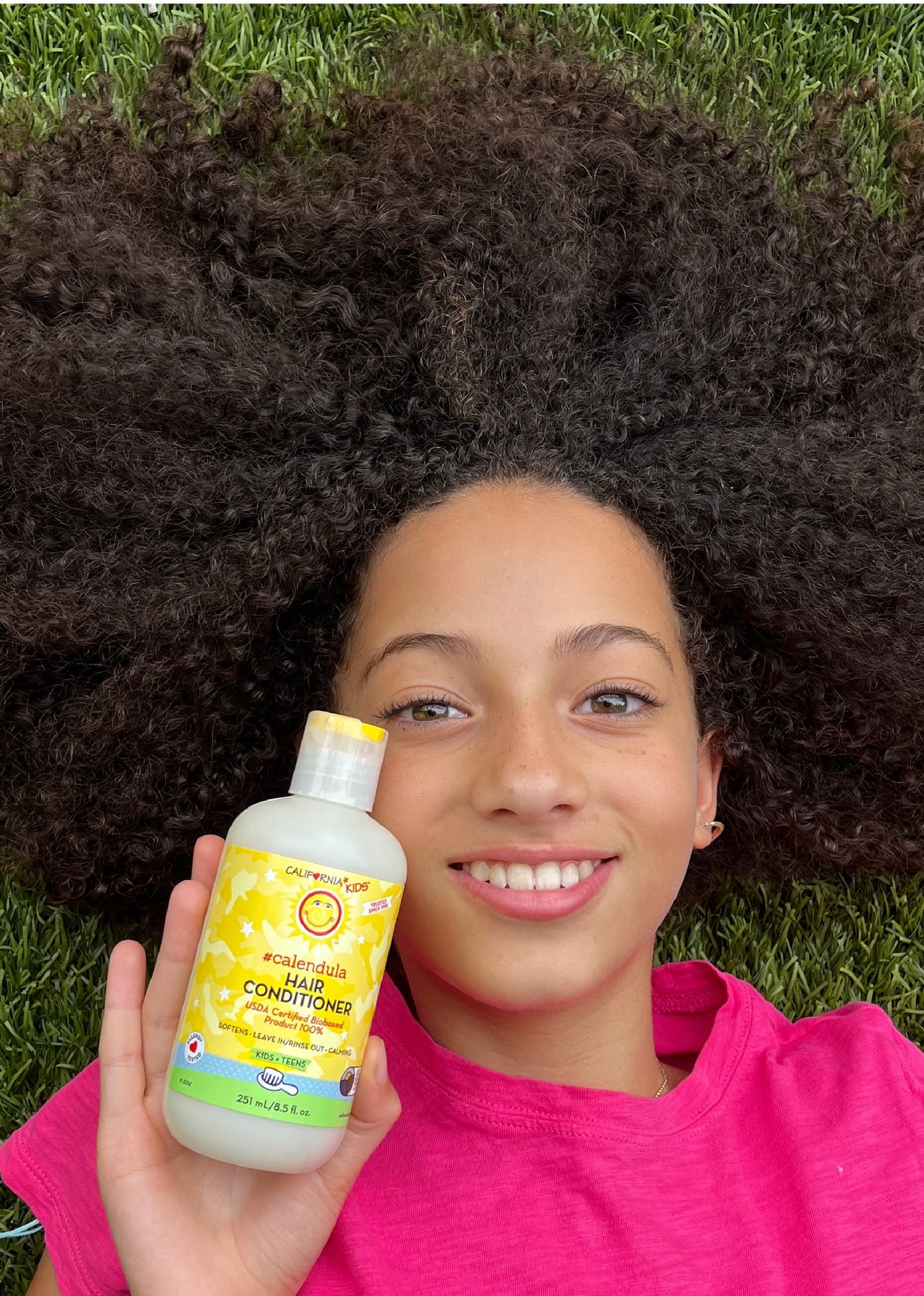 Kids Calendula hair conditioner bottle in hand, yellow label close-up