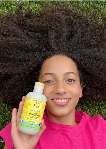 Kids Calendula hair conditioner bottle in hand, yellow label close-up