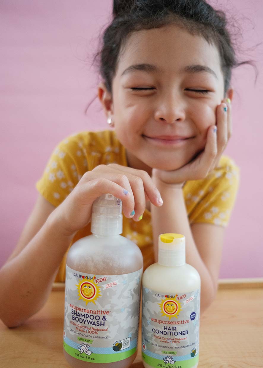 Kids fragrance-free shampoo and conditioner bottles held by child