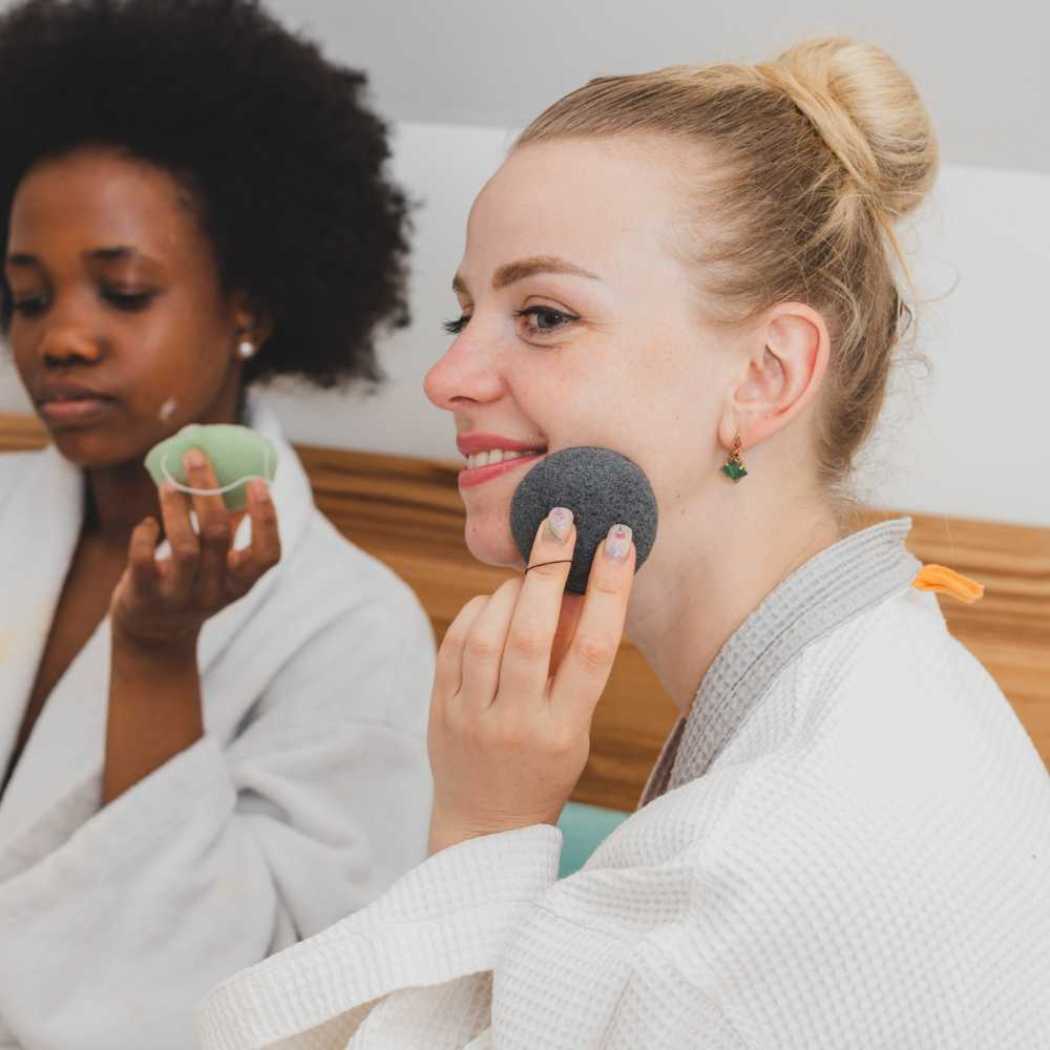 Konjac facial sponge held on face during cleansing, dark gray.