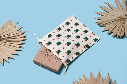White cloth gift bag with green-red gift icons, folded with drawstring closure