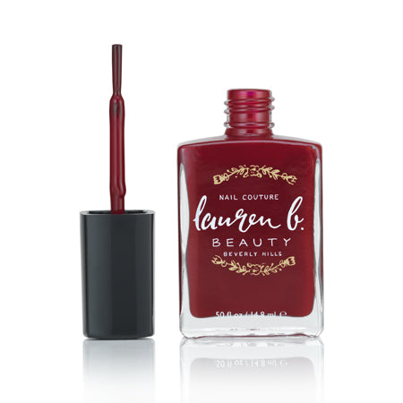 Burgundy vegan nail polish bottle with brush applicator and black cap.
