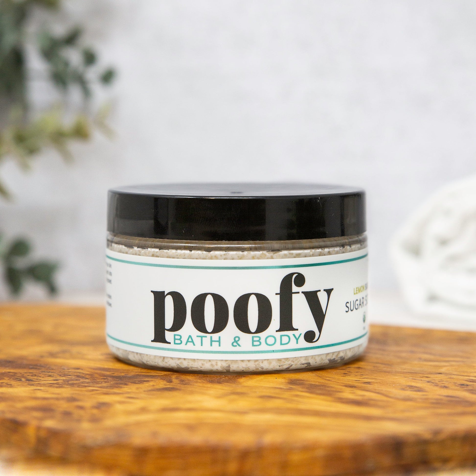 Cream sugar scrub in white jar with black lid, turquoise label accents.