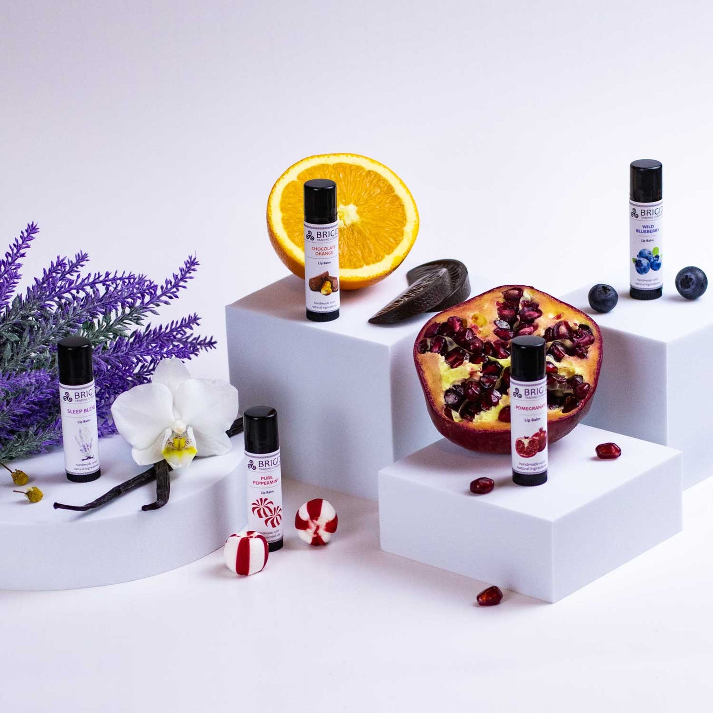 Sleep Blend lip balm tubes on white display with fruit and berry accents