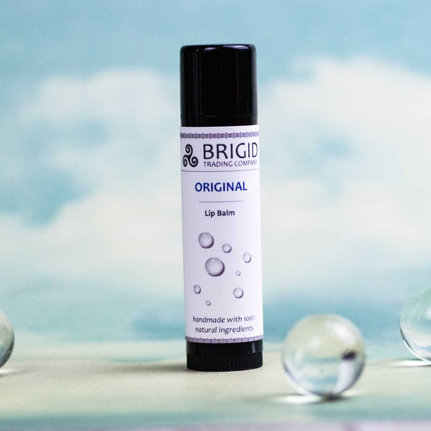Original natural lip balm stick in black cap, white label with blue accents