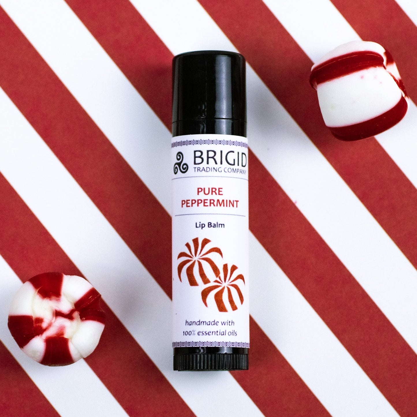 Peppermint lip balm tube with black cap and BRIGID label, shown with peppermint candy