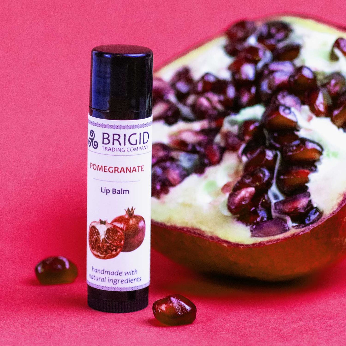 Pomegranate lip balm tube with black cap, white label, and pomegranate graphic