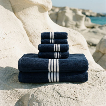 Folded navy cotton towels with white striped bands stacked on a stone