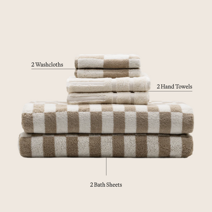 Striped cotton towels stack in tan and ecru; folded washcloths and bath sheets.