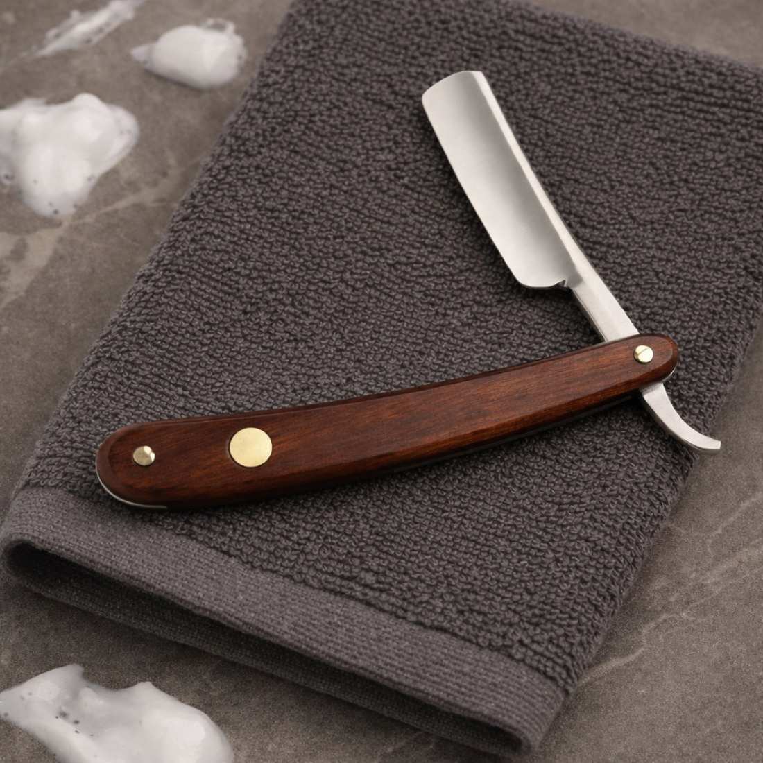 Straight razor with rosewood handle, silver blade, and gold decorative pins