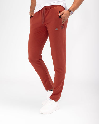 Tapered athletic sweatpants in rust red, elastic waistband, cuffed ankle, side pockets.