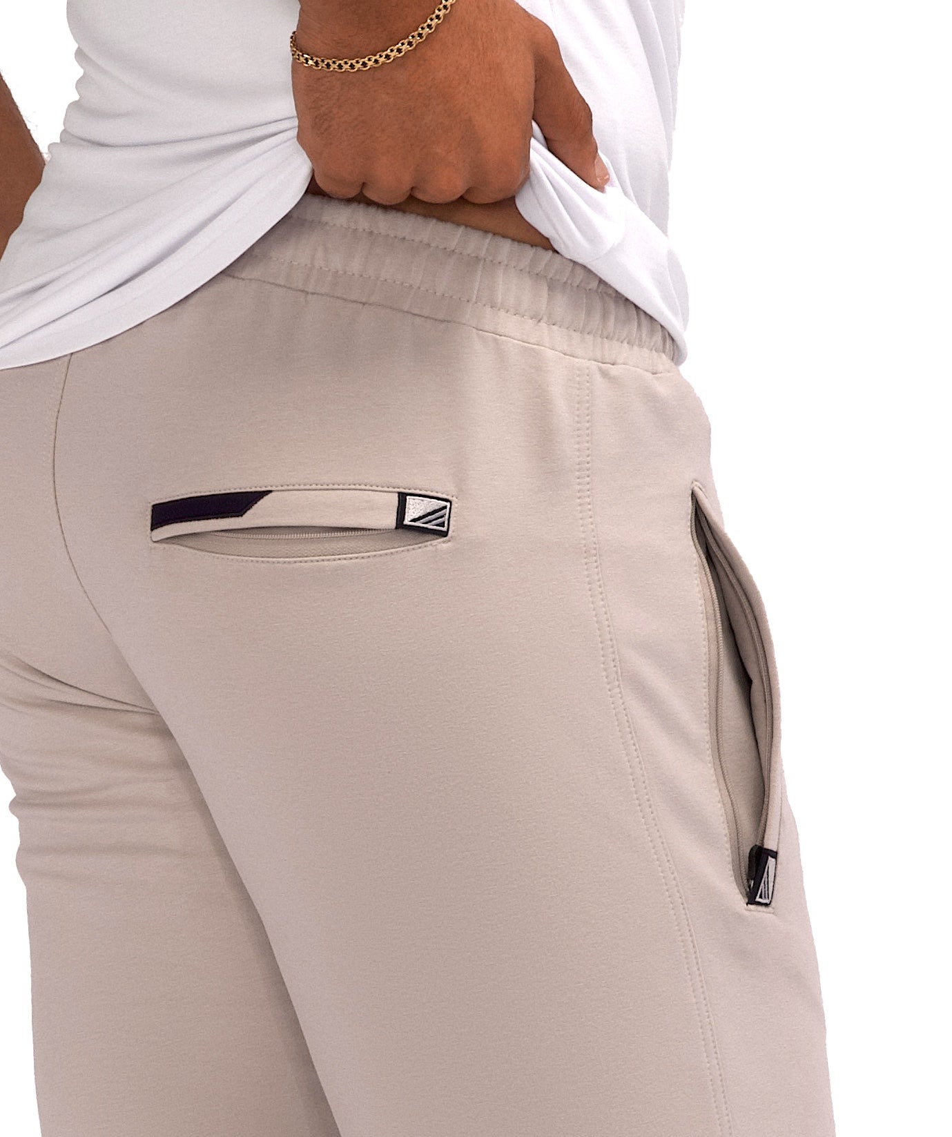 Athletic sweatpants with side pockets and elastic waistband; light khaki with logo details.