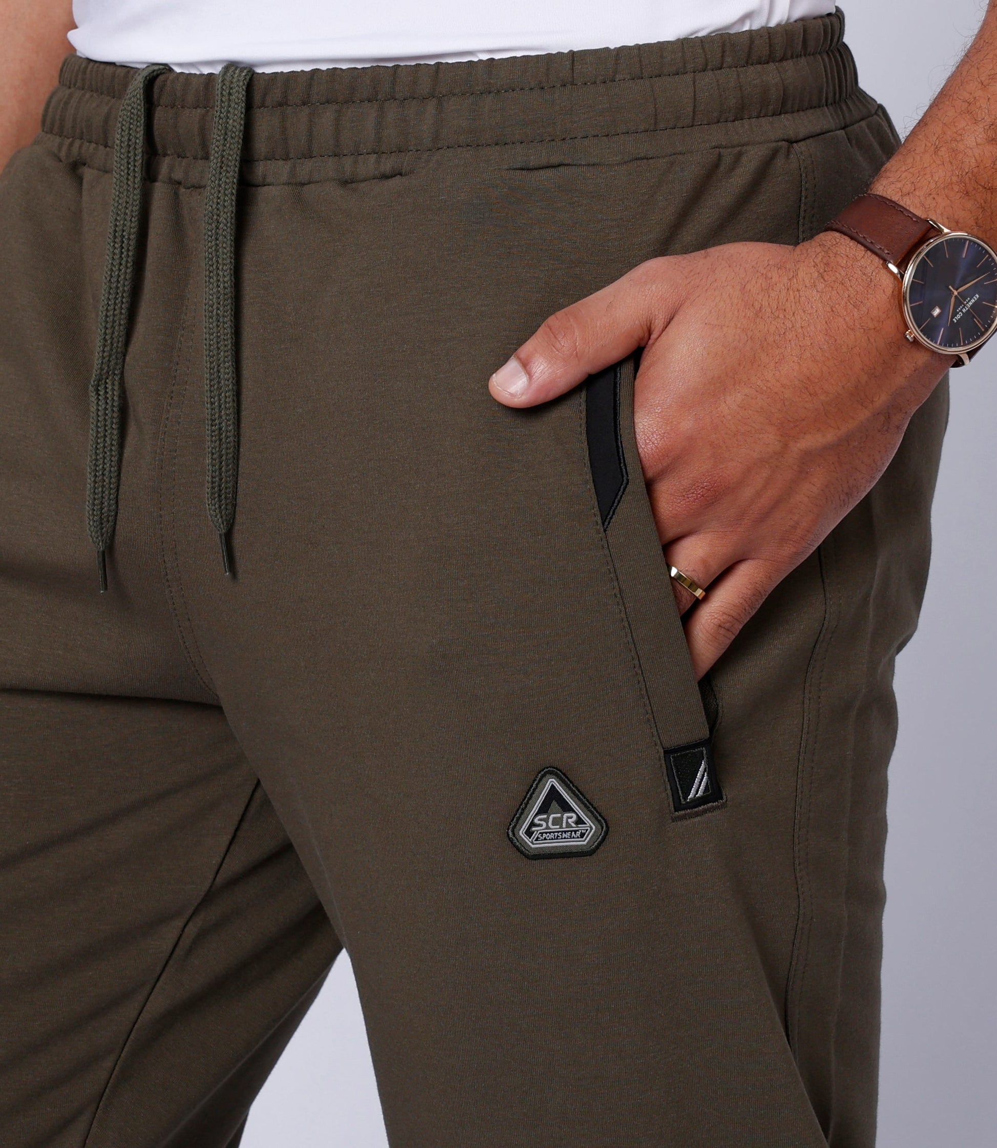 Khaki green sweatpants close-up: elastic waist, drawstring, side and back logo details