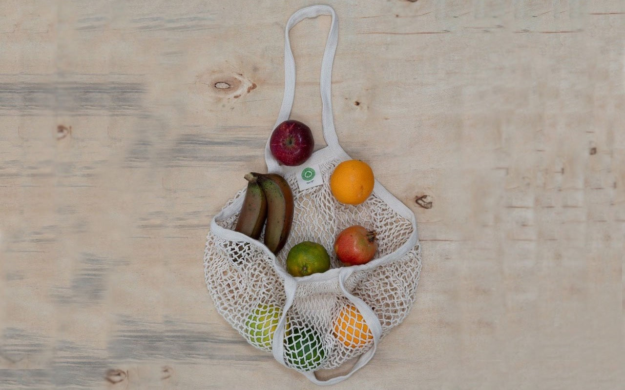 Mesh tote bag with long handles, filled with assorted fruits and vegetables