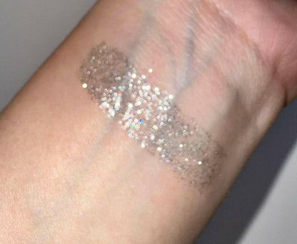 Glitter eyeliner swatch on skin with fine silver sparkles along a diagonal