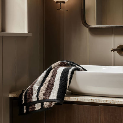Striped plush towel draped over a bathroom fixture, with dark and white vertical stripes.
