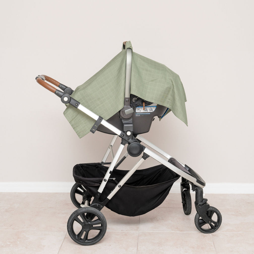 Green muslin car seat cover fitted on stroller, all-over checkered fabric panels