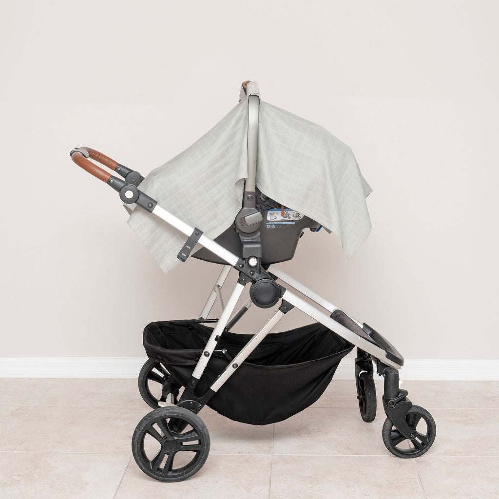 Muslin car seat cover in gray, mounted on stroller with side drape