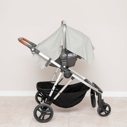 Muslin car seat cover in gray, mounted on stroller with side drape