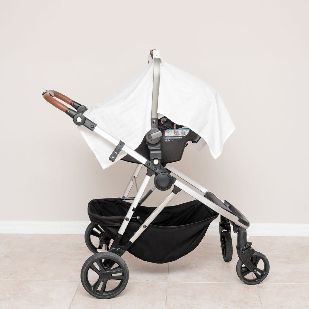 Muslin car seat cover in white, mounted on stroller with side drape