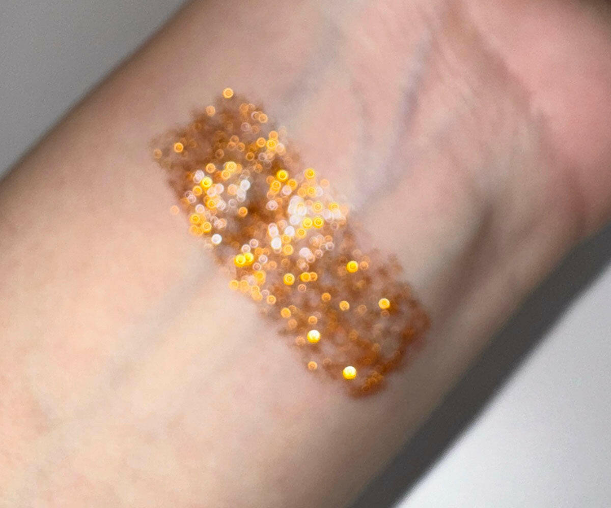 Gold glitter eyeliner swatch on skin with sparkling texture
