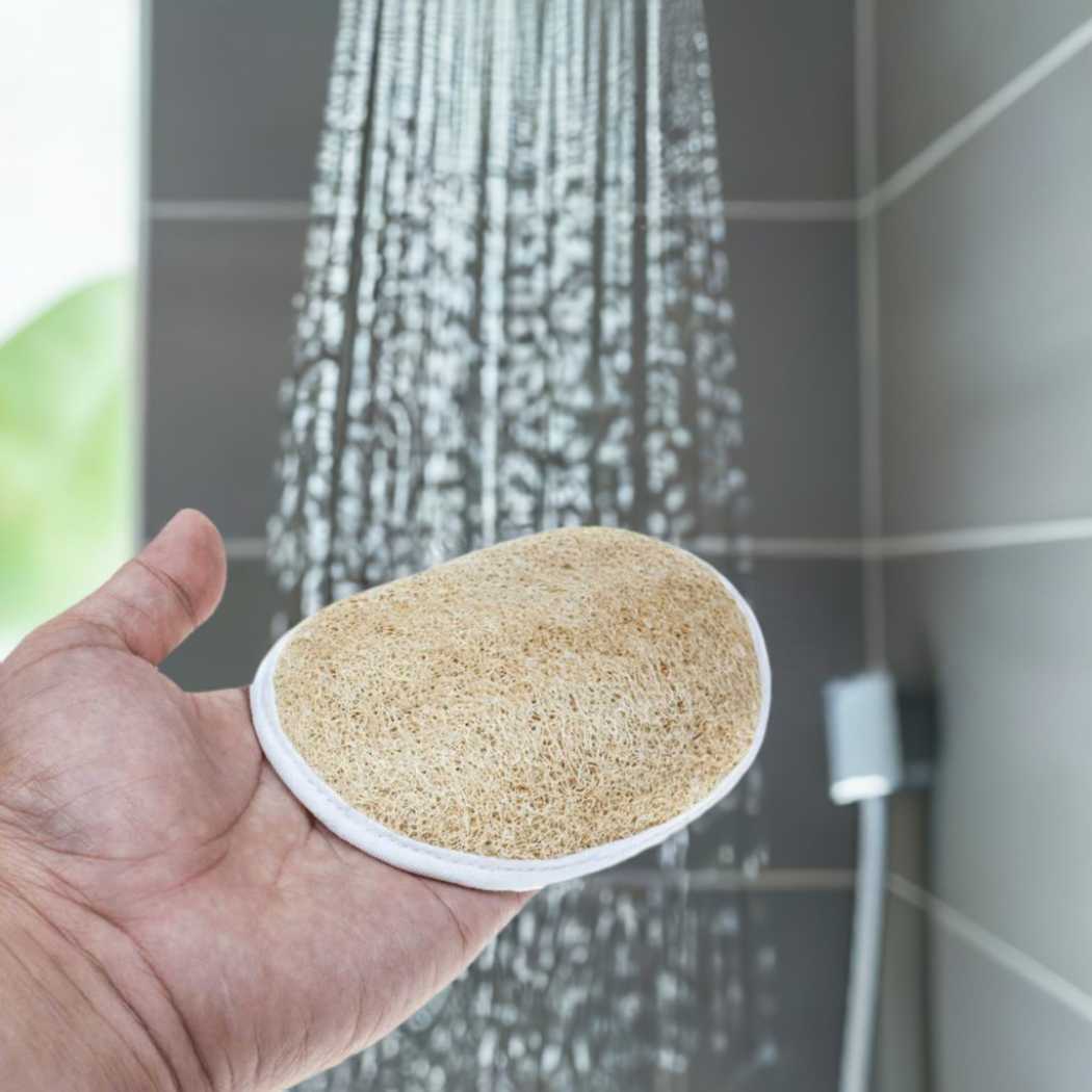 Loofah scrub pad, oval with loop, held in hand