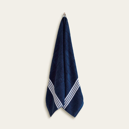 Navy cotton towel with white striped borders, hanging upright view.