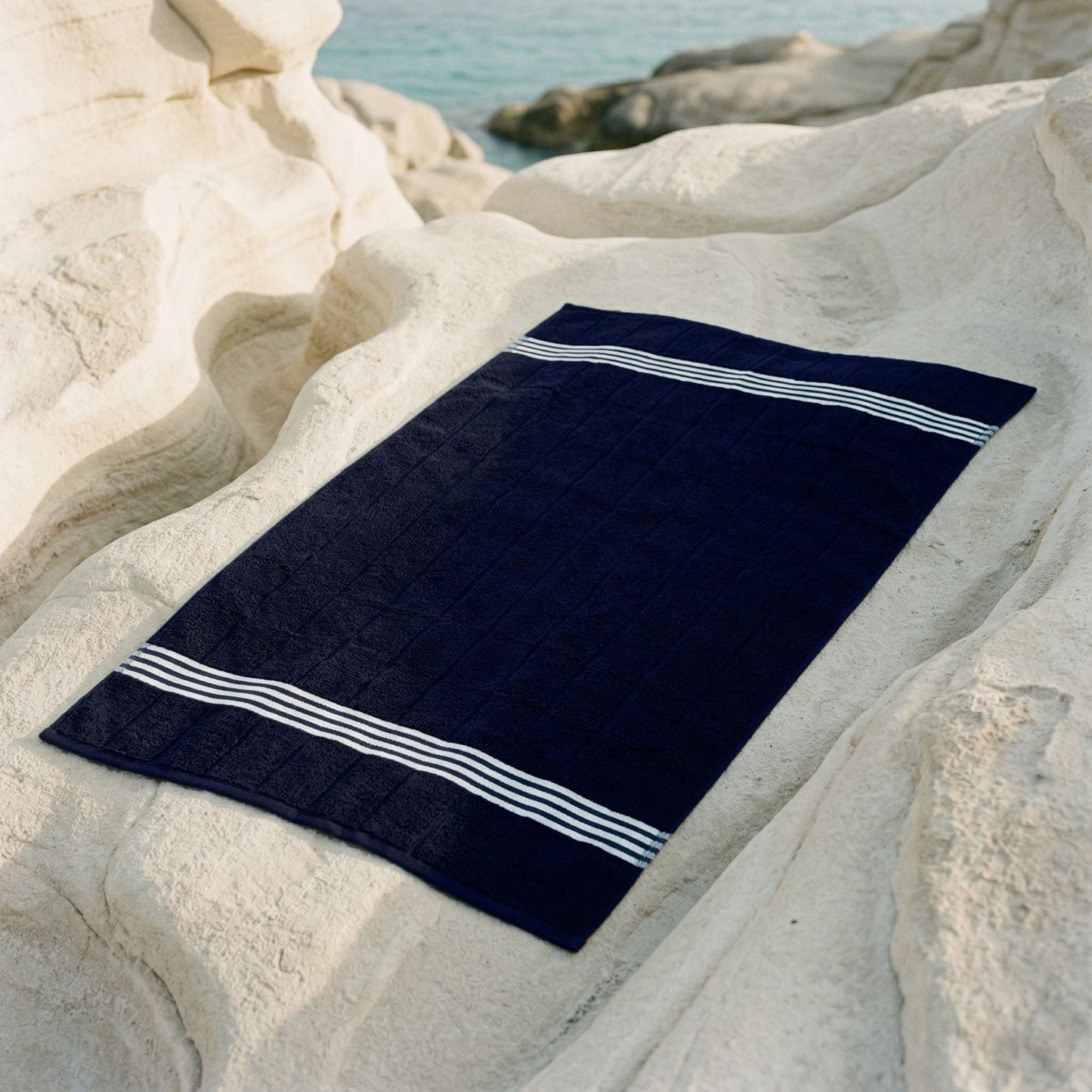 Navy cotton towel with white striped borders, laid flat.