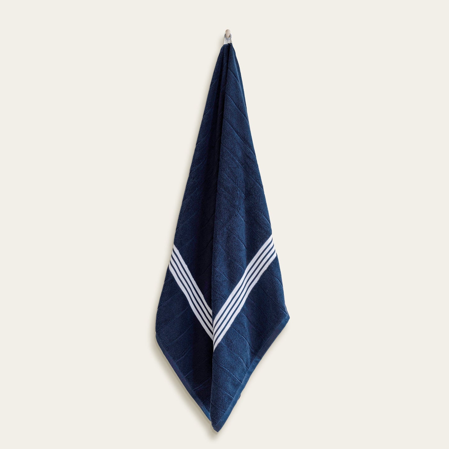 Navy cotton towel with white striped borders, hanging upright.