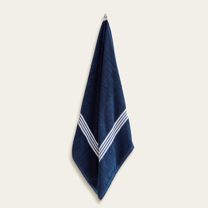 Navy cotton towel with white striped borders, hanging upright.