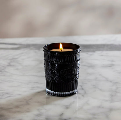 Lit black ribbed glass scented candle with white wax and flame