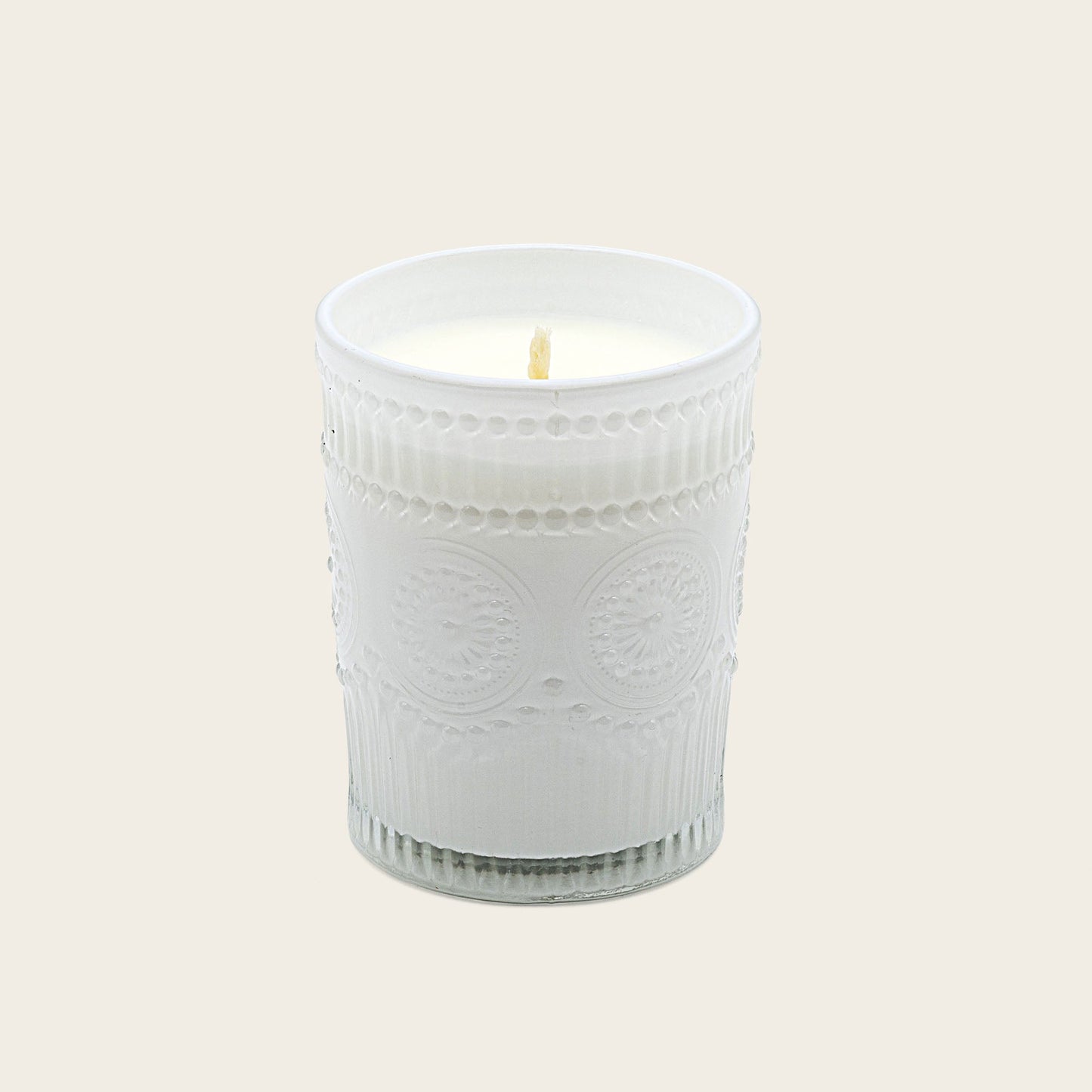 White embossed glass scented candle, lit flame
